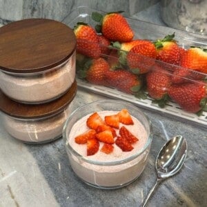 Blended Strawberry Overnight Oats in container with strawberries in background