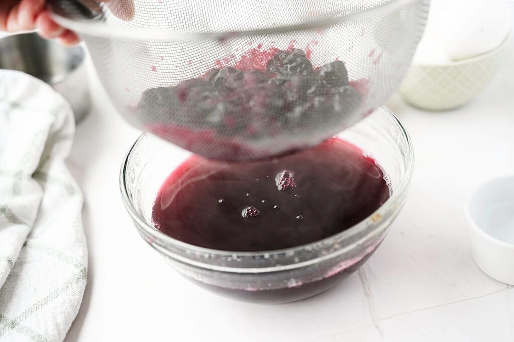 Blueberry dye juice being poured throug strainer