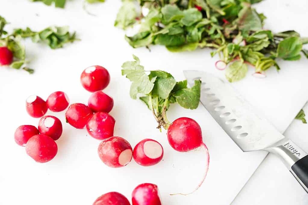 Cutting the radish greens on a white cutting board