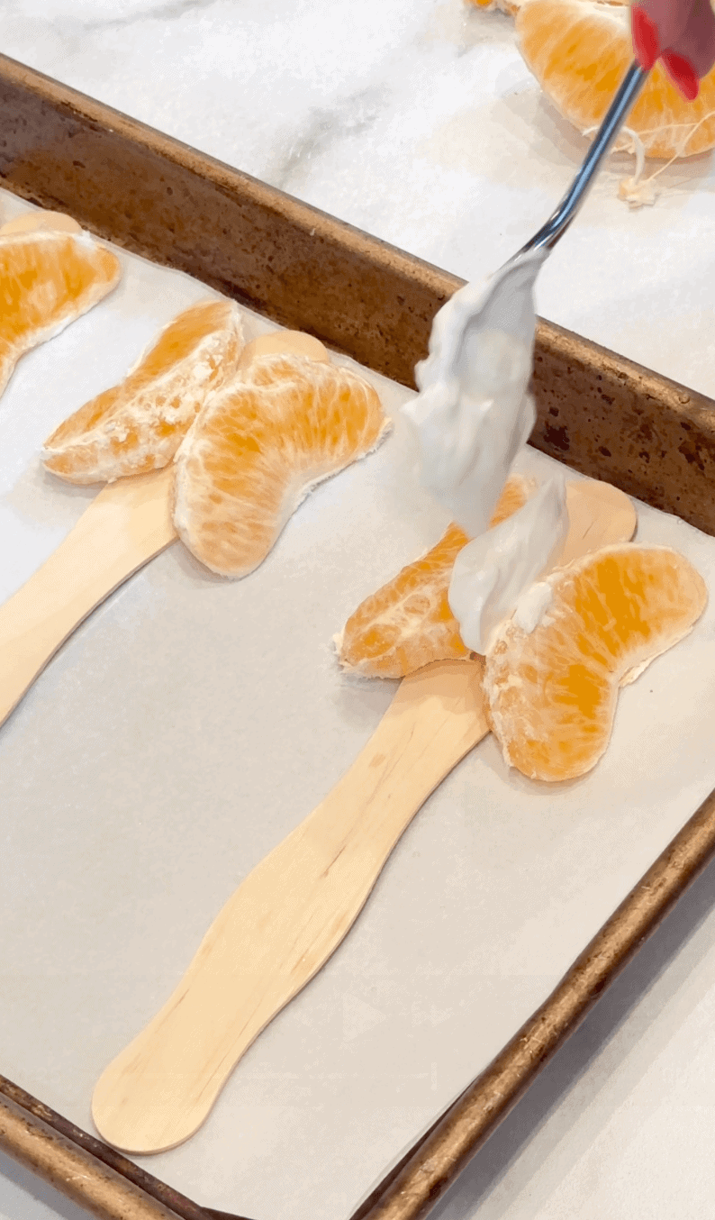 Layering Greek yogurt between two mandarin slices to hold them together