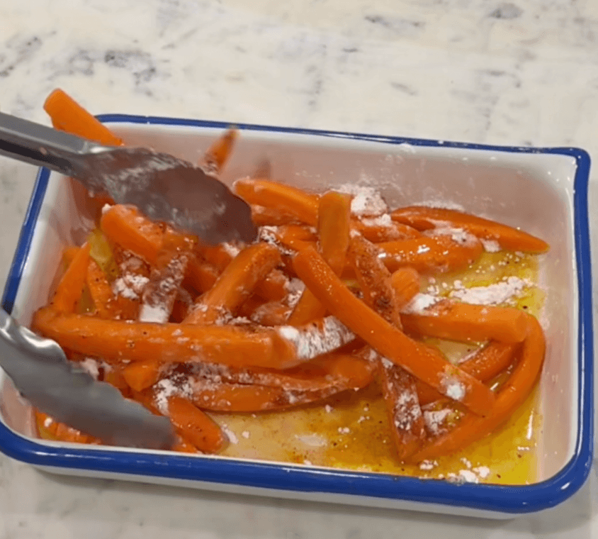 stirring the carrot sticks with olive oil and seasoning