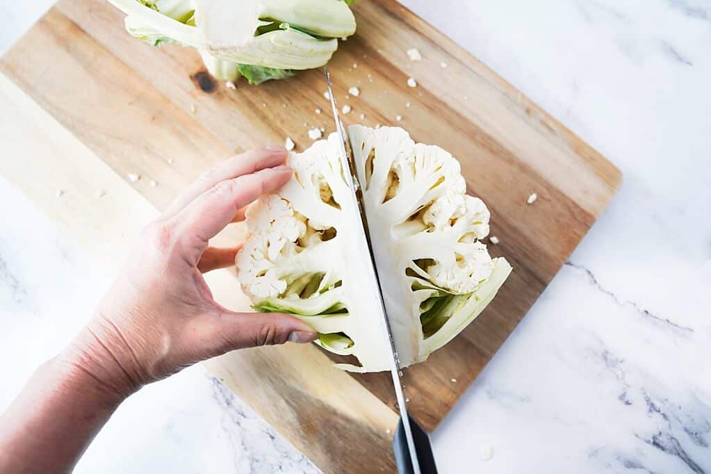 Taking half a head of cauliflower and cutting it into 1/4s
