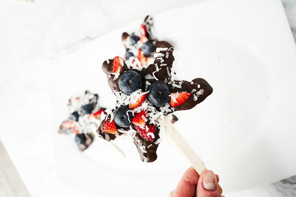 Close up for a homemade chocolate star with strawberries, blueberries and coconut shreds