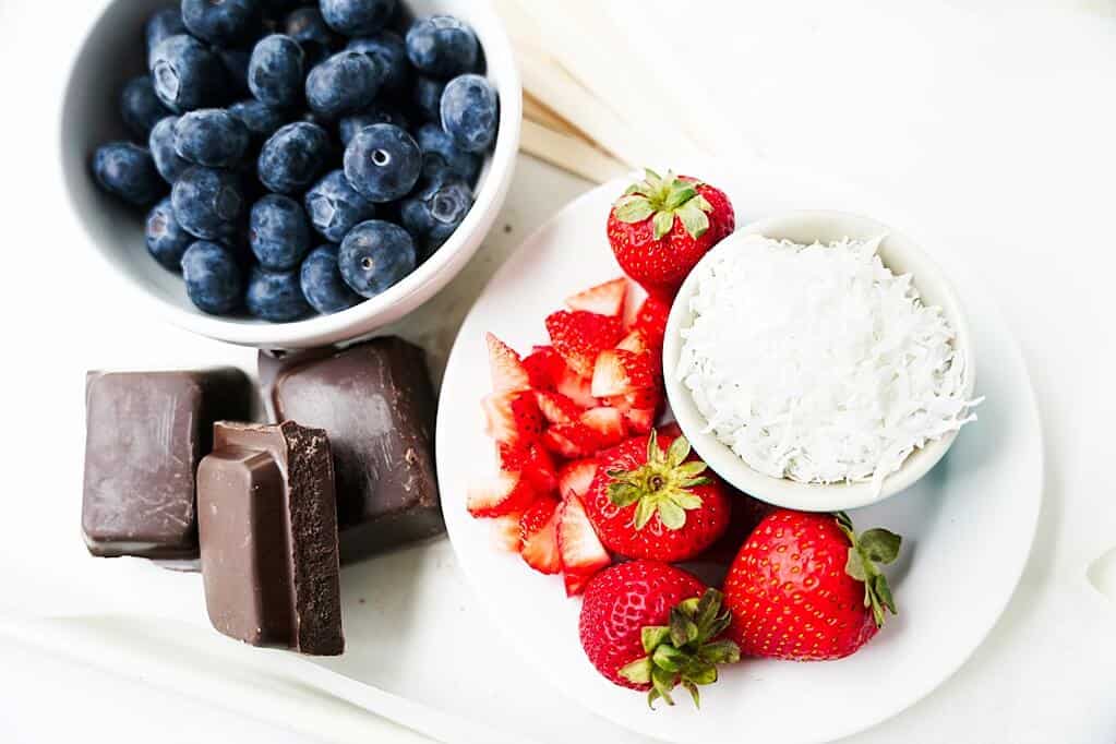 Ingredients to make Homemade Chocolate Stars: blueberries, strawberreis, coconut shreds, chocolate squares