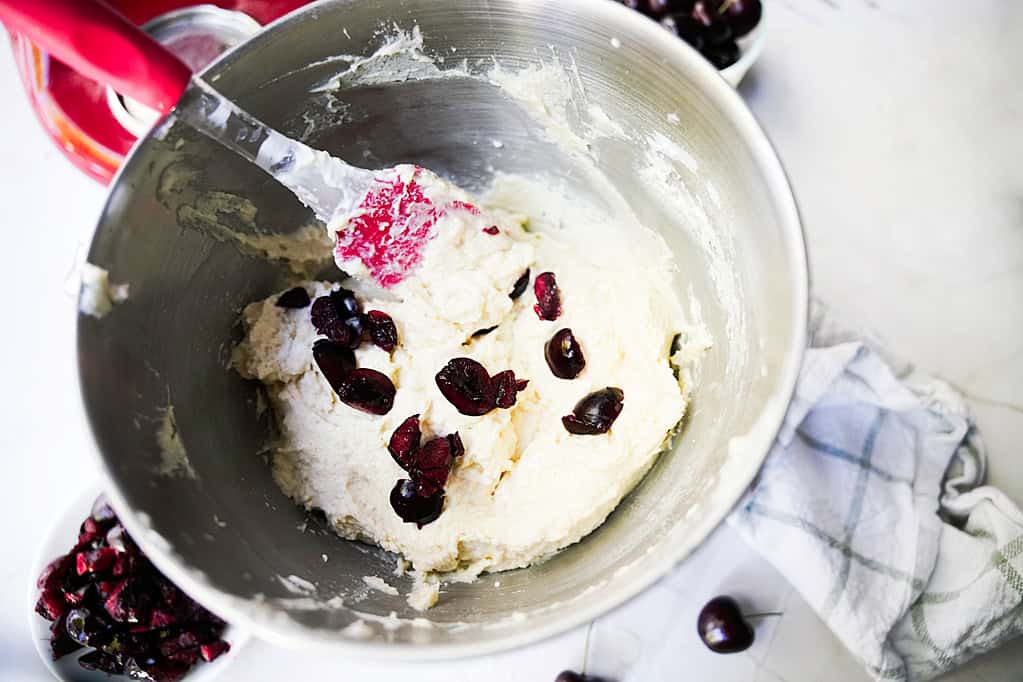 Cherry halves folded into the cherry bread batter with a spatula in the stand mixer.