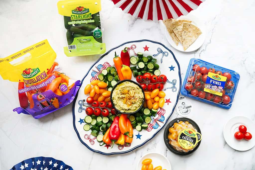 Summer veggie platter with cucumbers, tomatoes, and bell peppers served with hummus dip