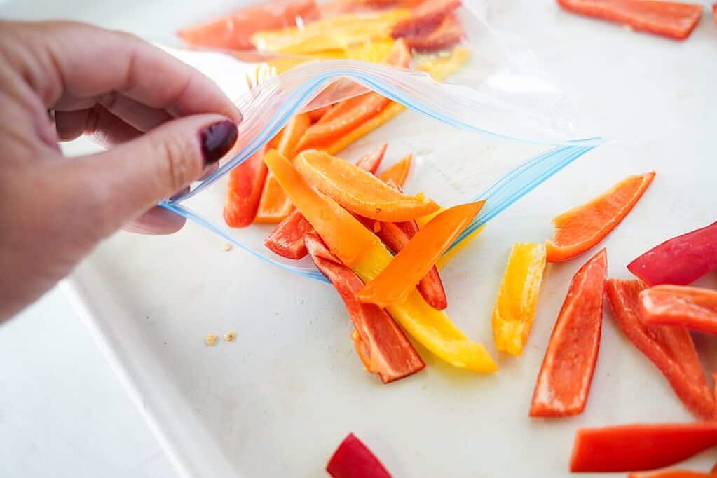 Strips of mini sweet peppers going into bag to freeze