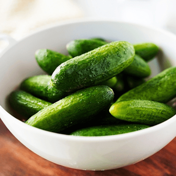 White bowl of whole baby cucumbers