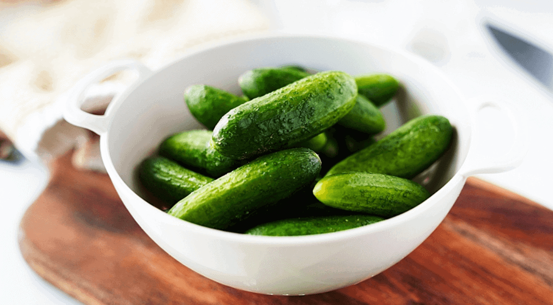 White bowl of whole baby cucumbers