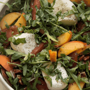 Vertical shot of peach burrata salad in white bowl