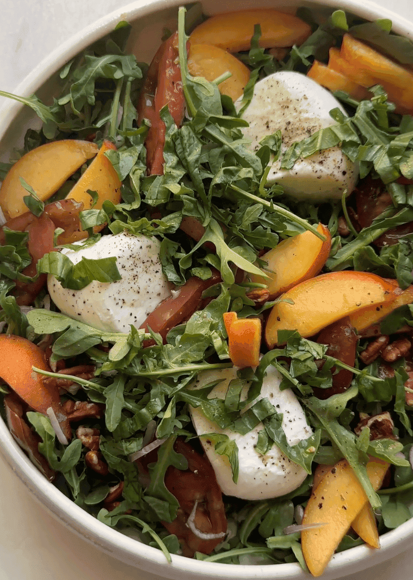 Vertical shot of peach burrata salad in white bowl