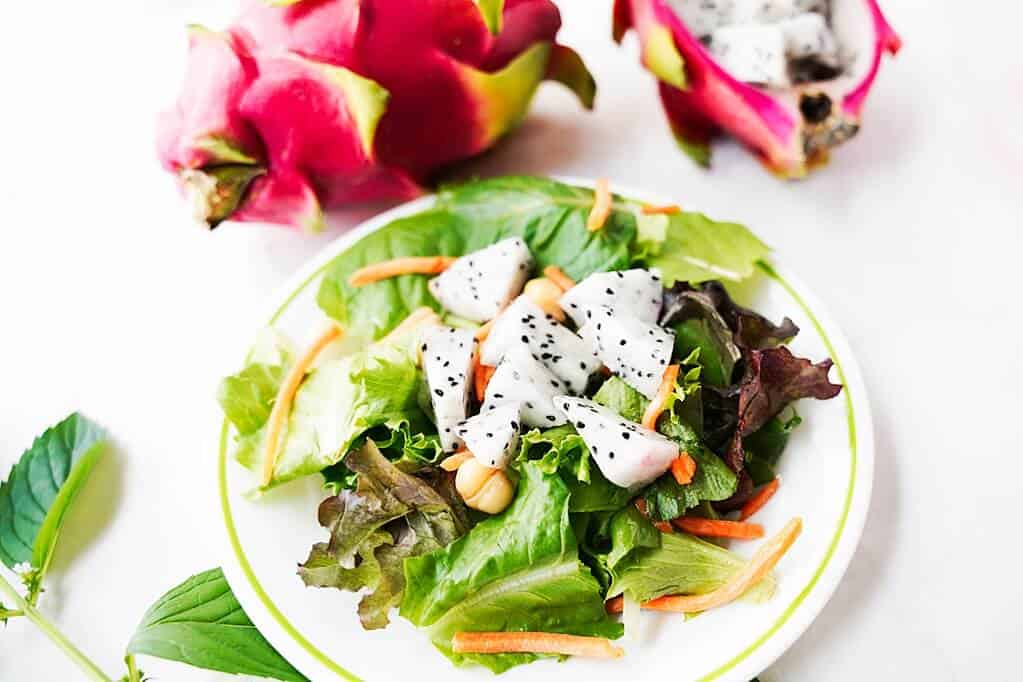 Cubed dragon fruit on a salad with dragon fruits in the background