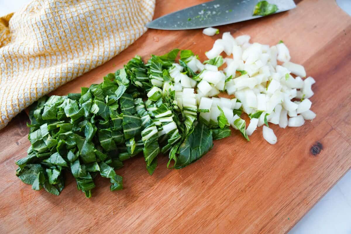 The stalk and leaves of bok choy chopped on a cutting board