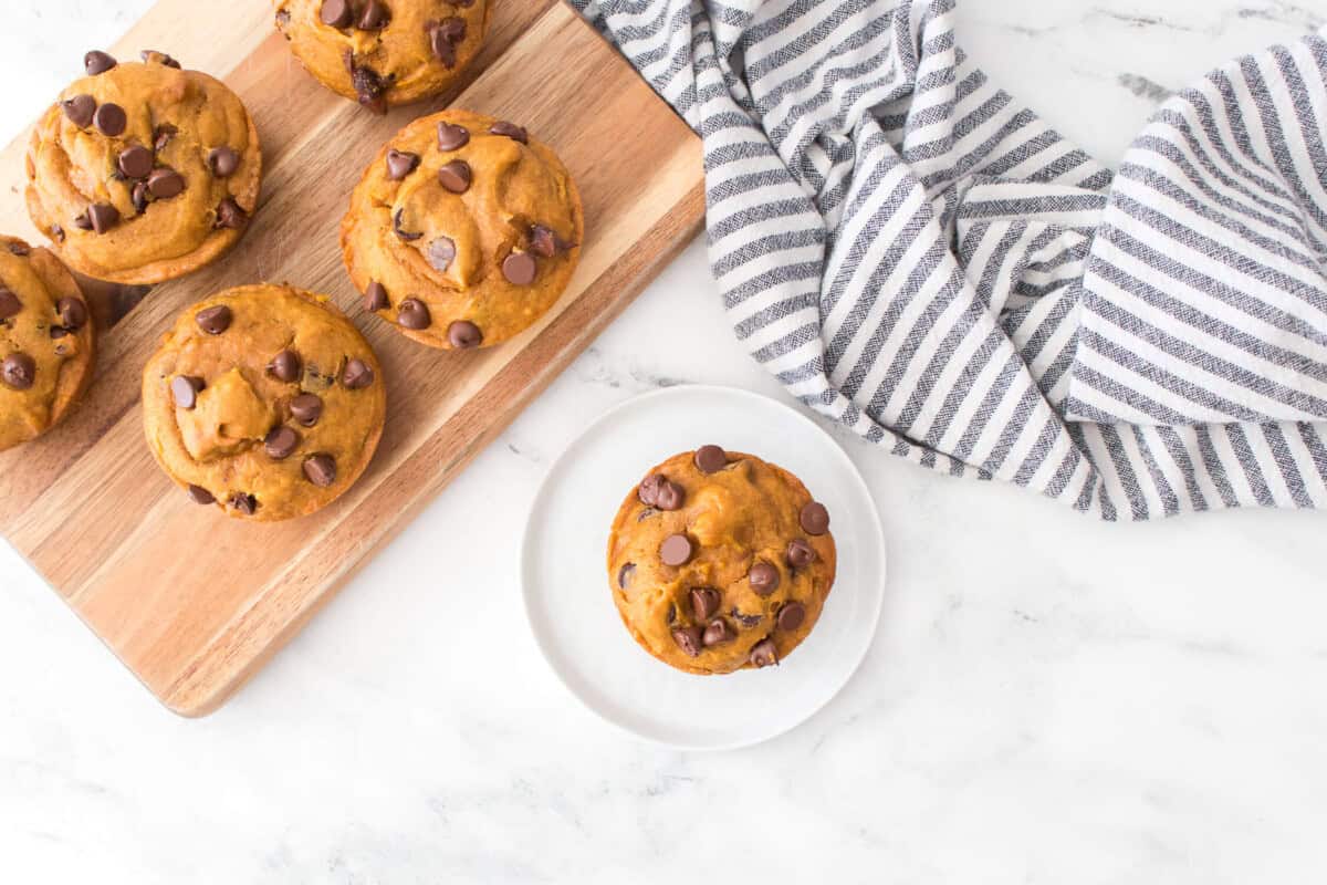 Overhead view of Chocolate Chip Pumpkin Muffins - one on plate and 5 more on a board